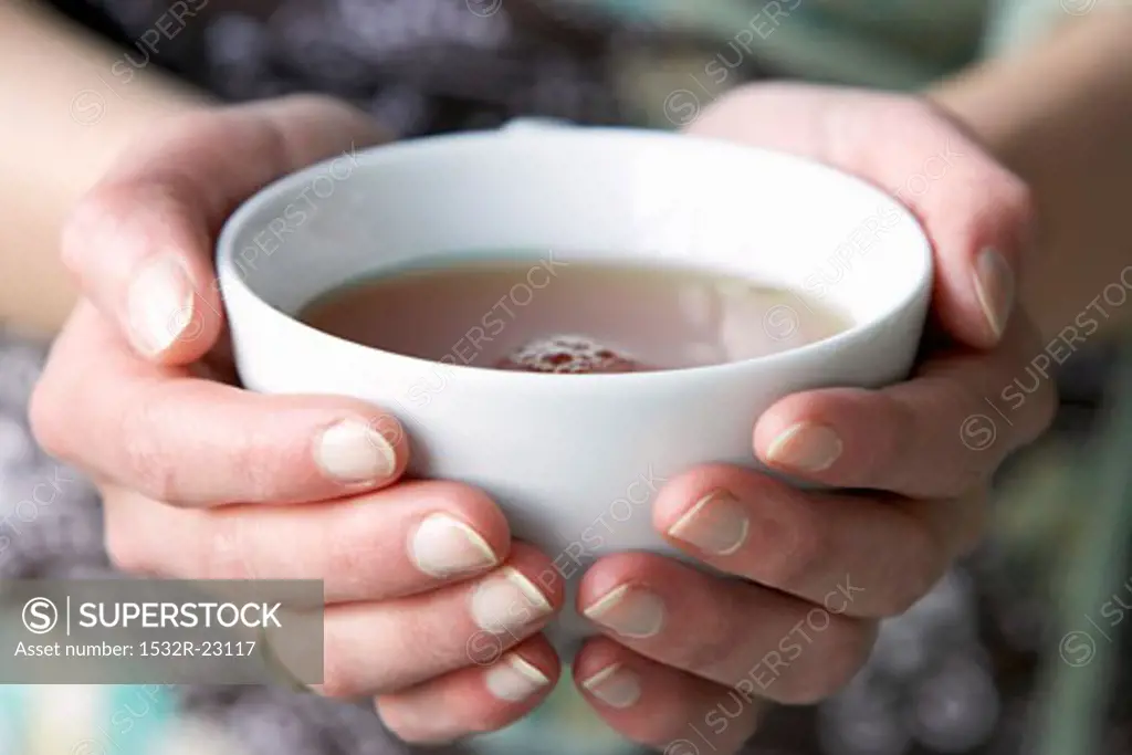 Two hands holding a cup of tea