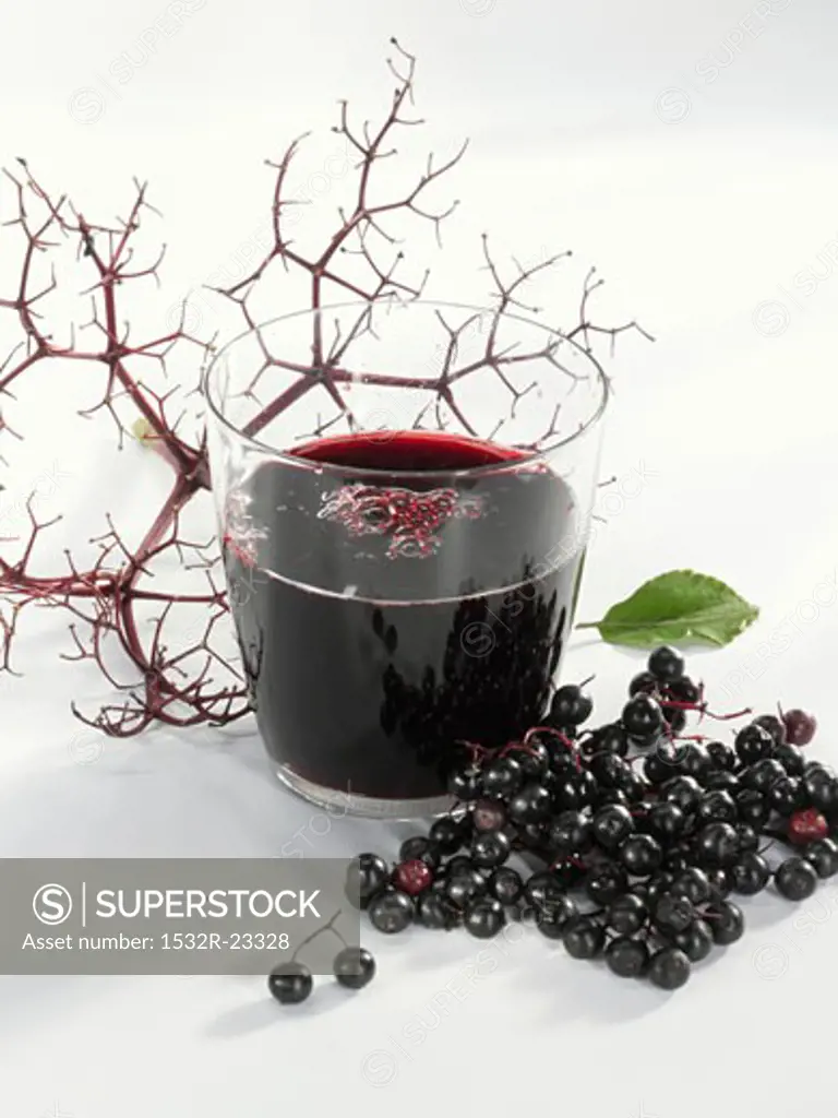 A glass of elderberry & apple juice & fresh elderberries