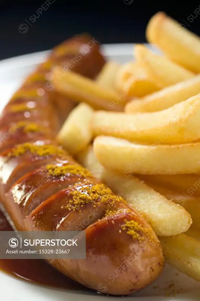 Currywurst with ketchup, curry powder and chips on a plate