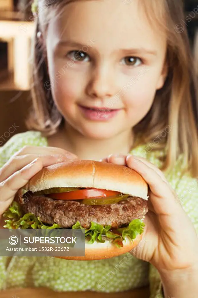 Small girl holding a hamburger in her hands