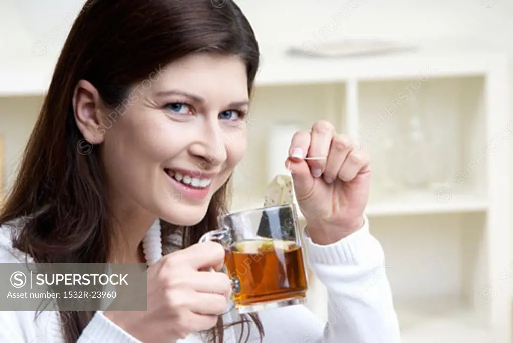 Woman holding cup of tea and tea bag in her hands