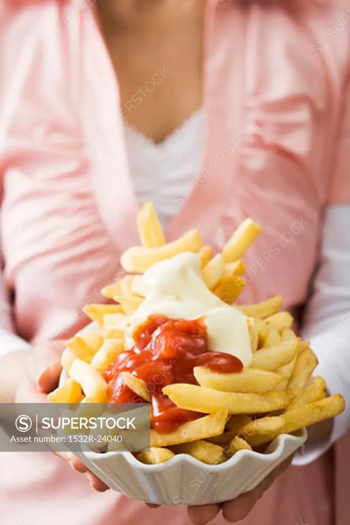 Chips with ketchup and mayonnaise in a china bowl
