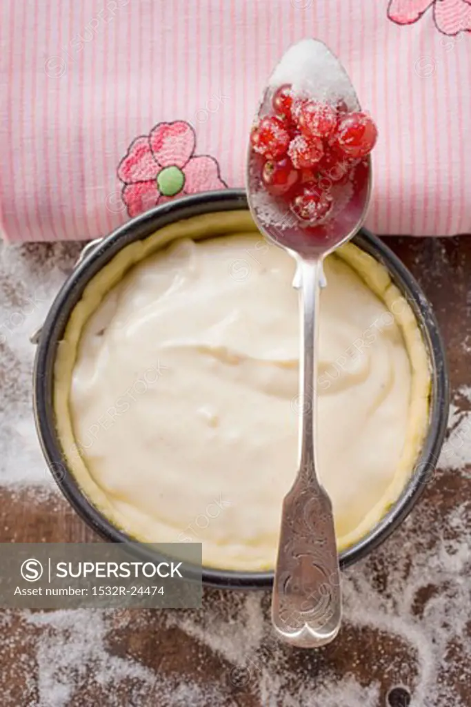 Baking tin with pastry & vanilla cream, redcurrants on spoon
