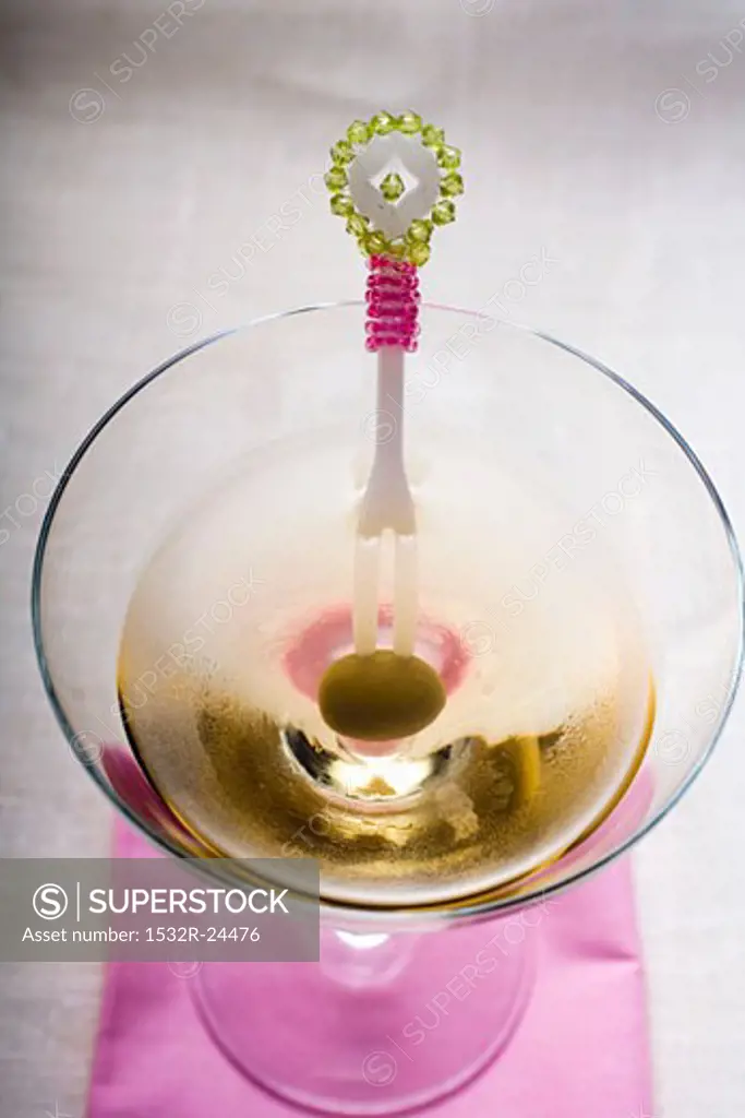Martini with green olive on cocktail fork