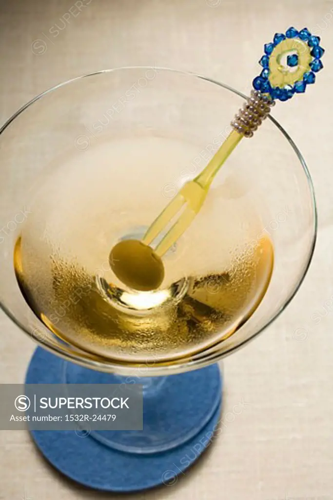 Martini with green olive on cocktail fork