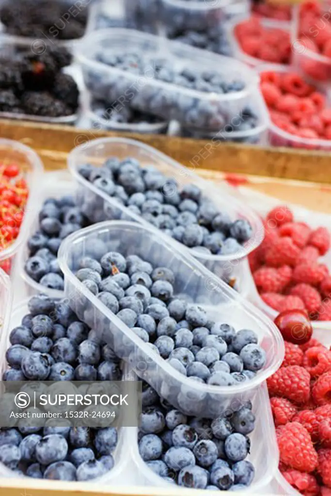 Blueberries and raspberries in plastic punnets at a market
