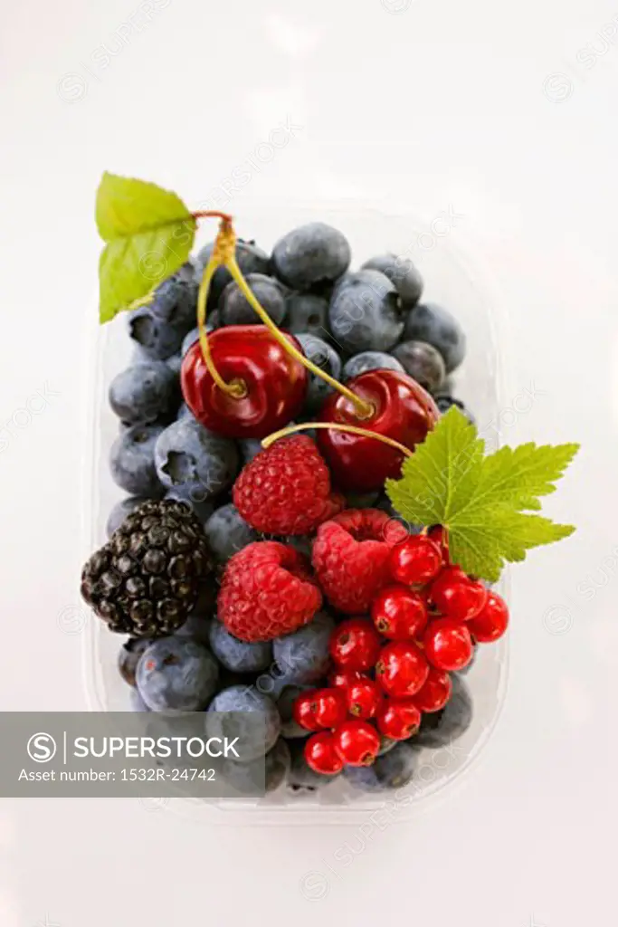 Assorted berries and two cherries in plastic punnet