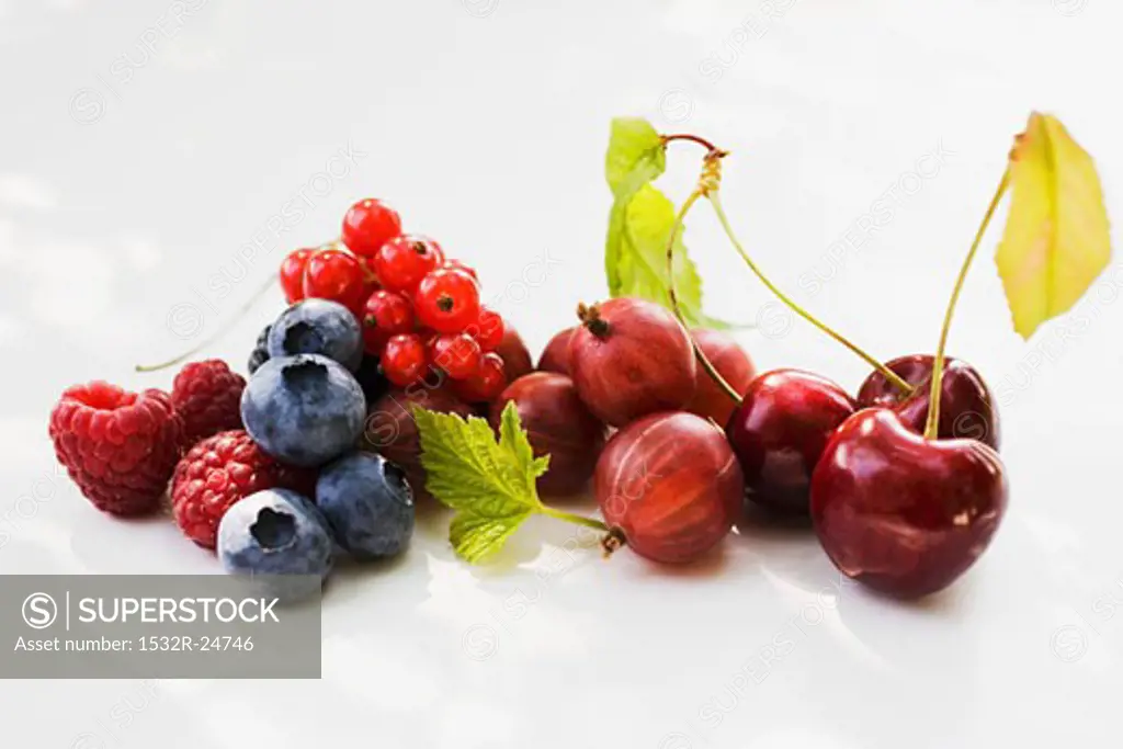 Assorted berries and three cherries with leaves