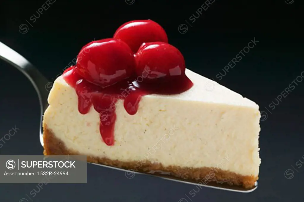 Slice of cheesecake with cherries on cake server