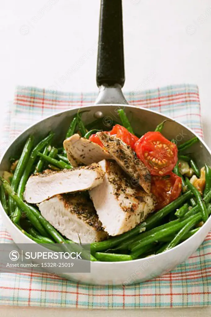 Chicken breast with green beans and tomatoes in frying pan