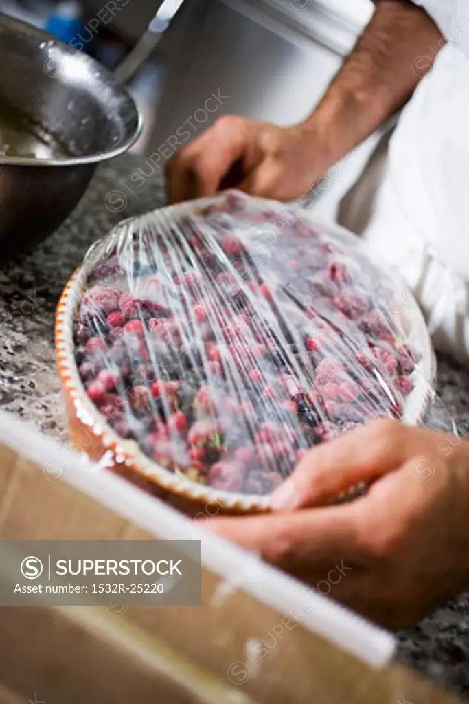 Covering berry dessert with cling film