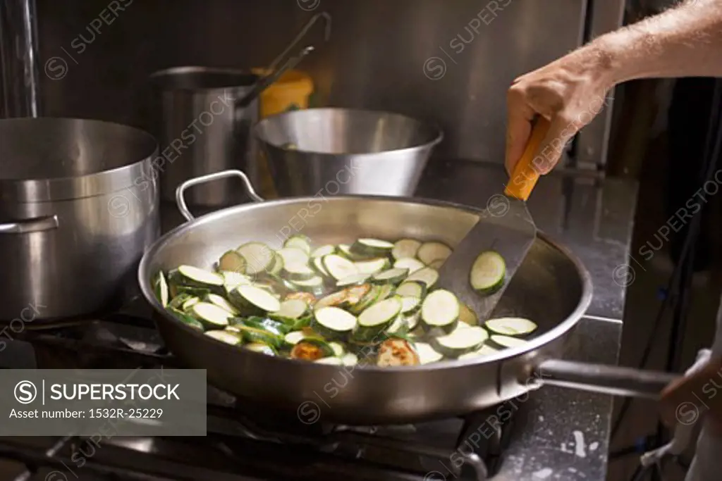 Turning courgette slices in frying pan