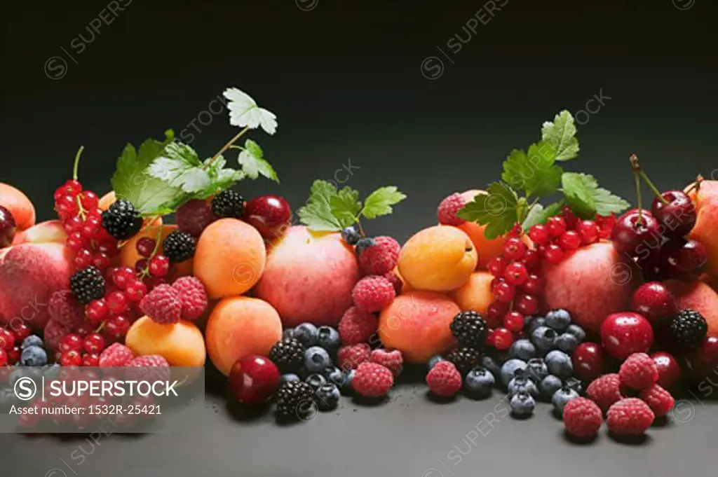 Fruit still life with stone-fruit, berries and leaves