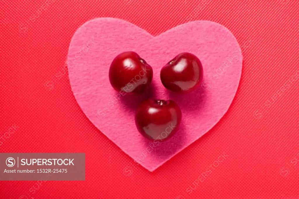 Three cherries on a pink fabric heart
