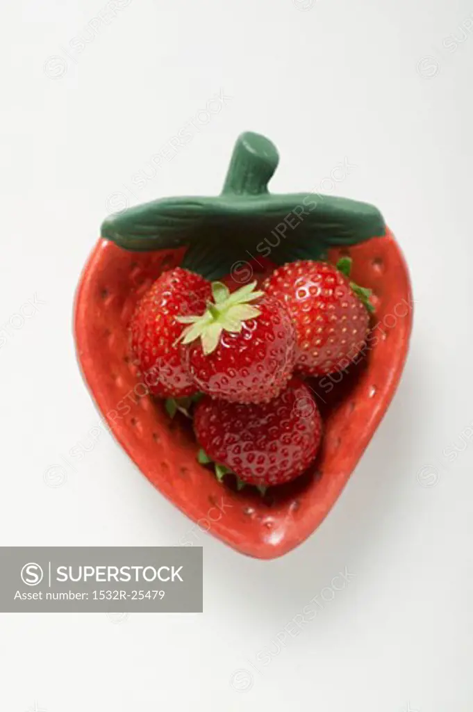 Four strawberries in red strawberry-shaped dish