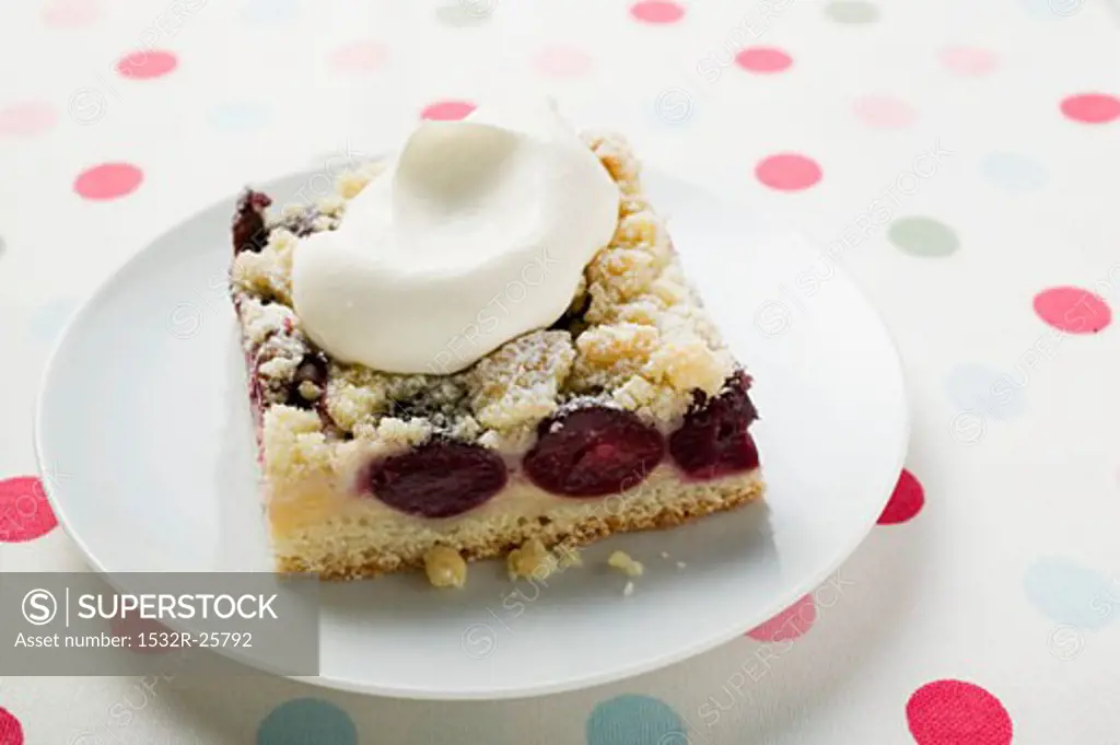 A piece of cherry crumble cake with cream