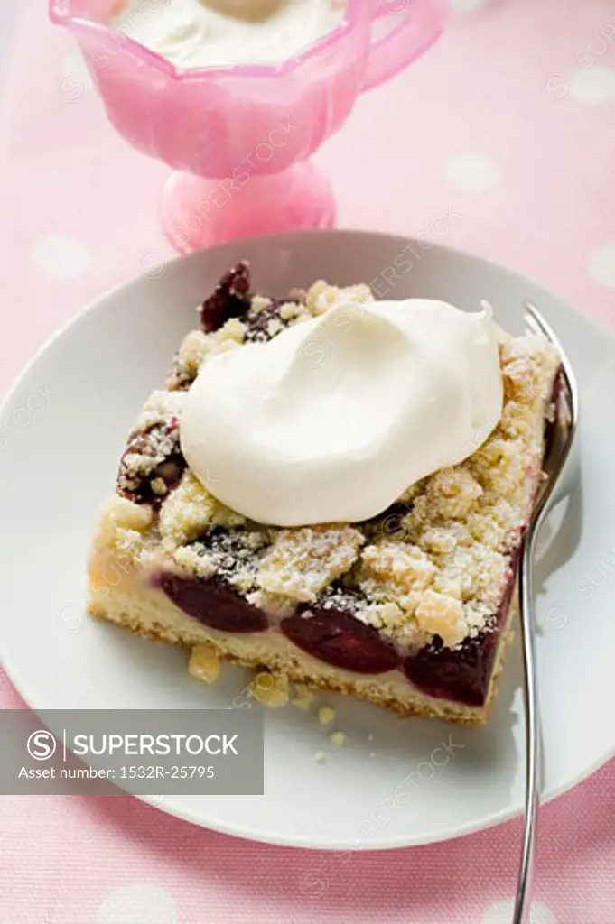 A piece of cherry crumble cake with cream