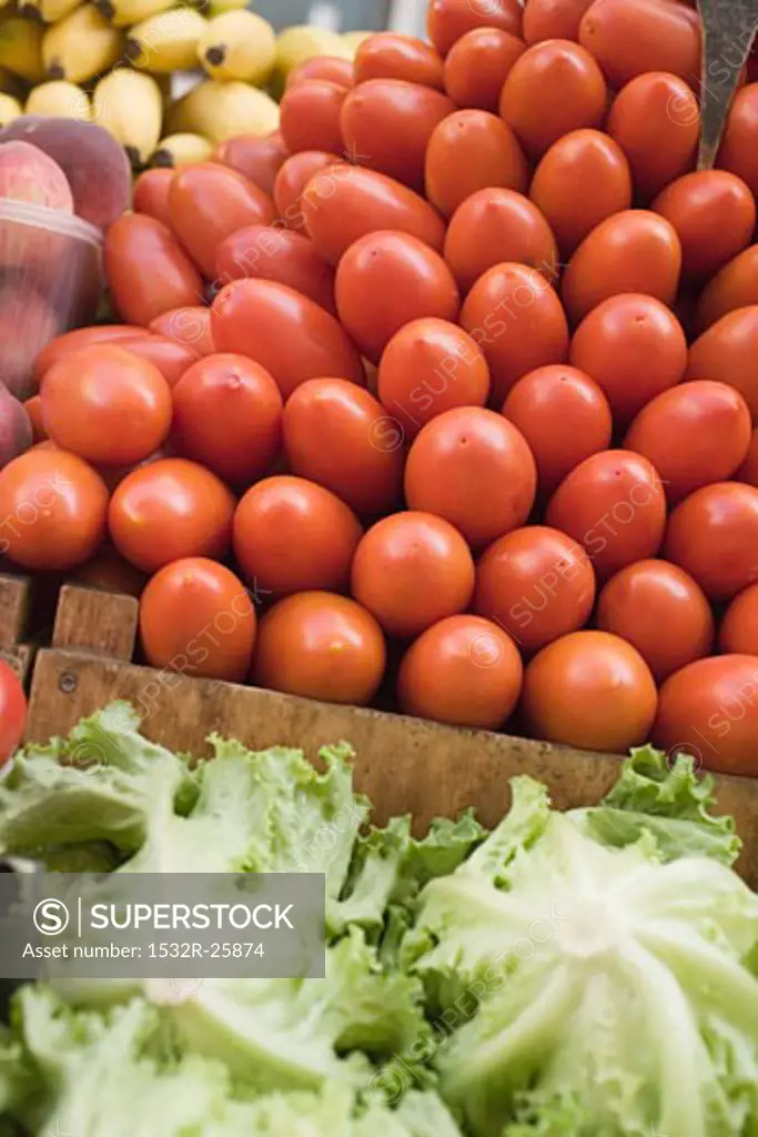 A heap of plum tomatoes in a crate at a market