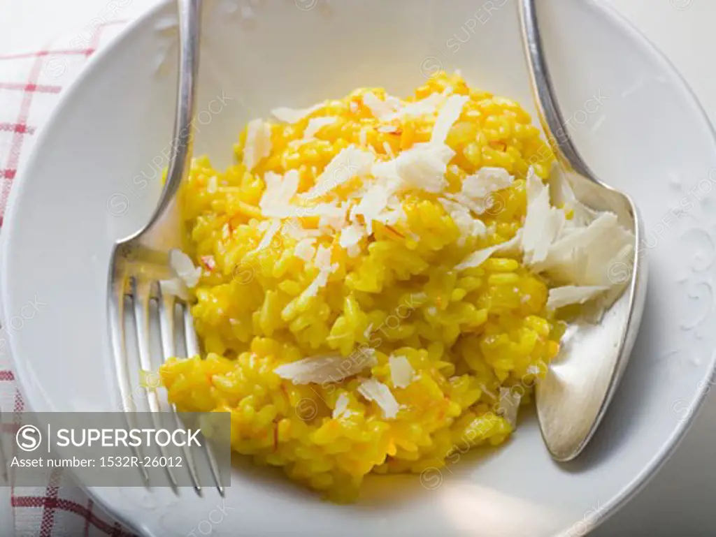 Saffron risotto with Parmesan on white plate with cutlery