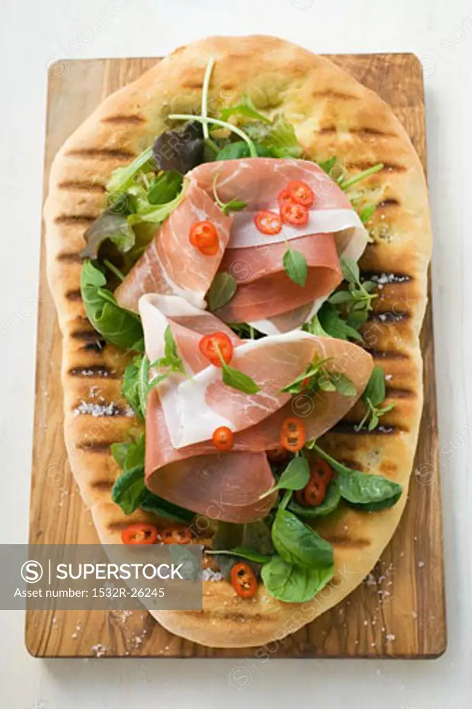 Parma ham, herbs and chili rings on pizza bread