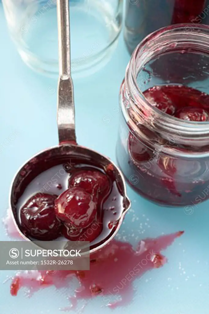 Ladling cherry jam into jars