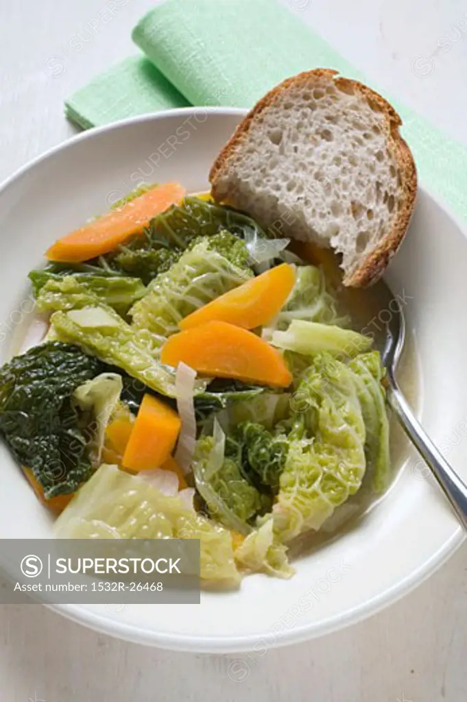 Savoy and carrot stew in soup plate, piece of bread