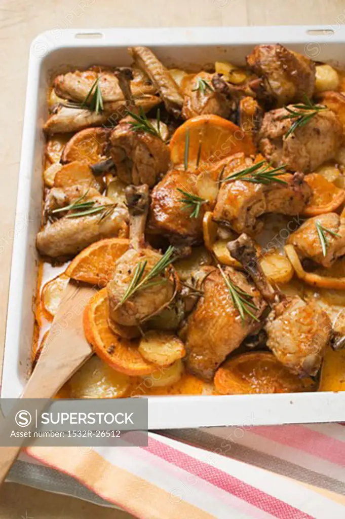 Chicken pieces with oranges and rosemary on baking tray
