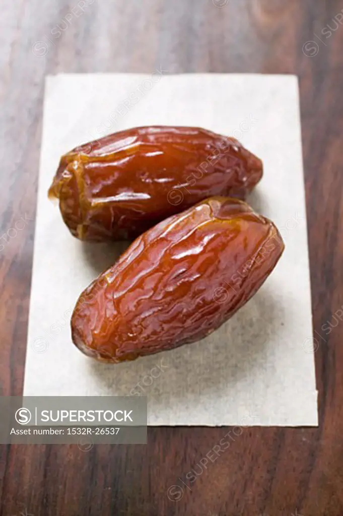 Two dried dates on paper