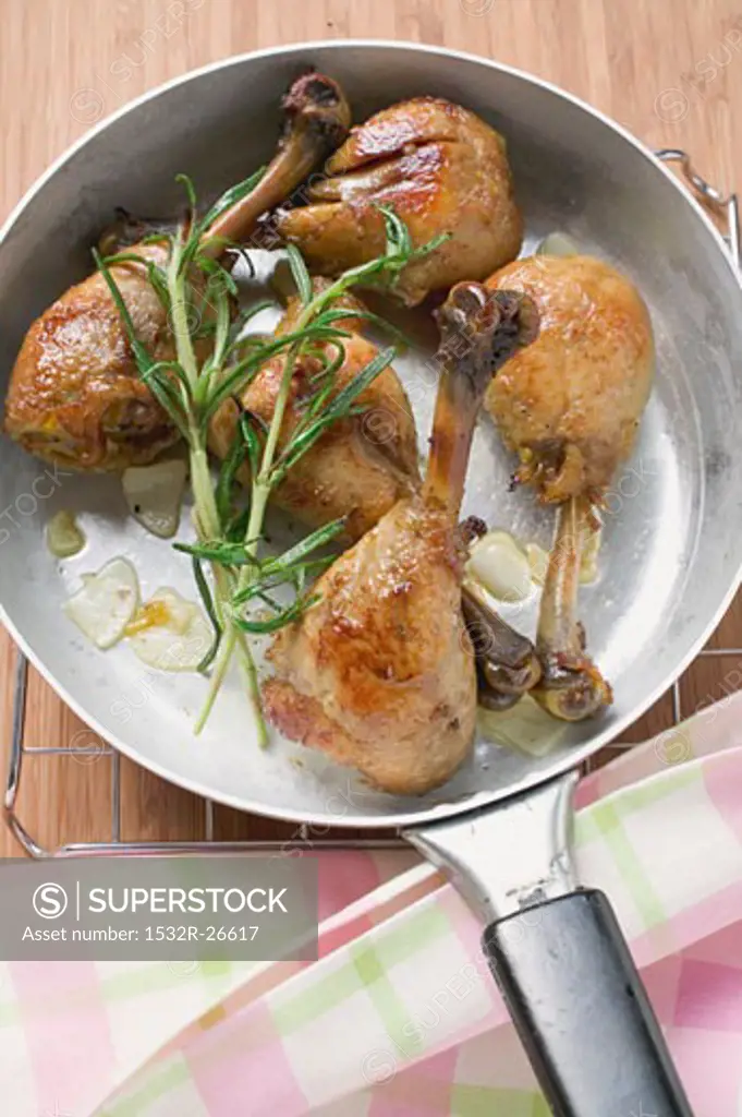 Fried chicken legs with rosemary in frying pan