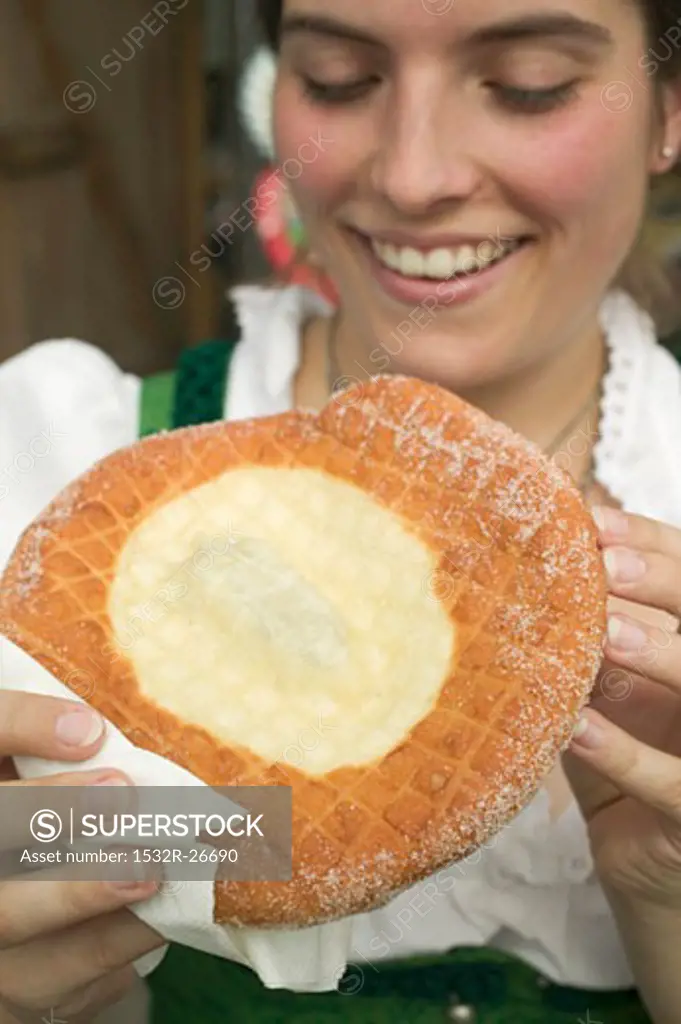 Woman eating Auszogene (type of doughnut) at Oktoberfest