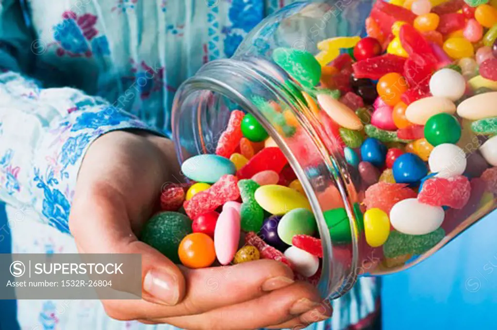 Person tipping sweets out of jar