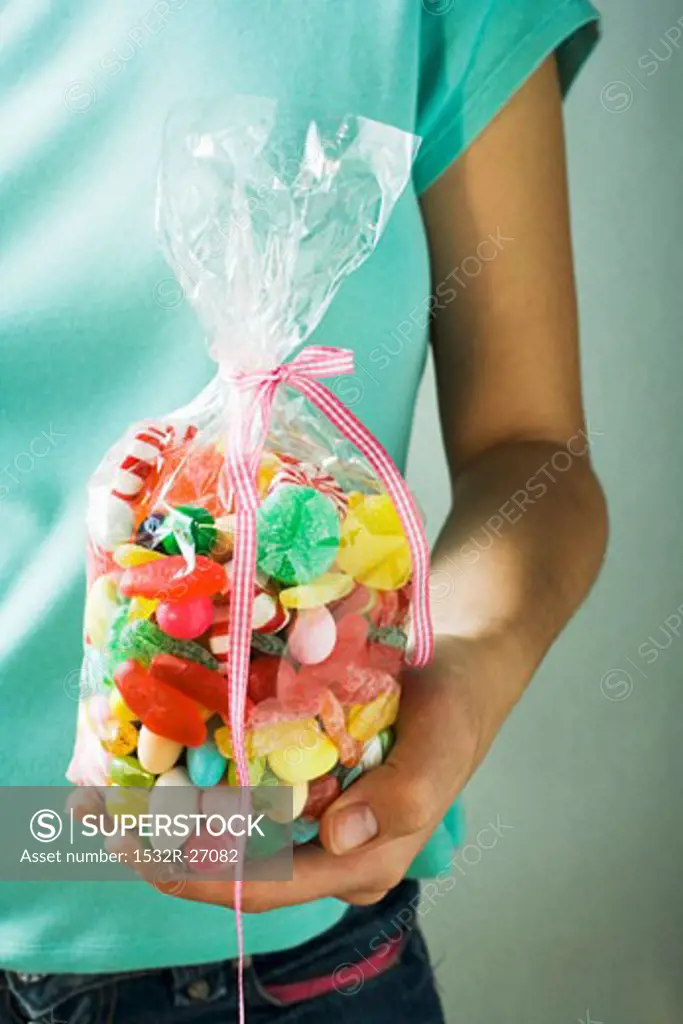 Hand holding cellophane bag of coloured sweets