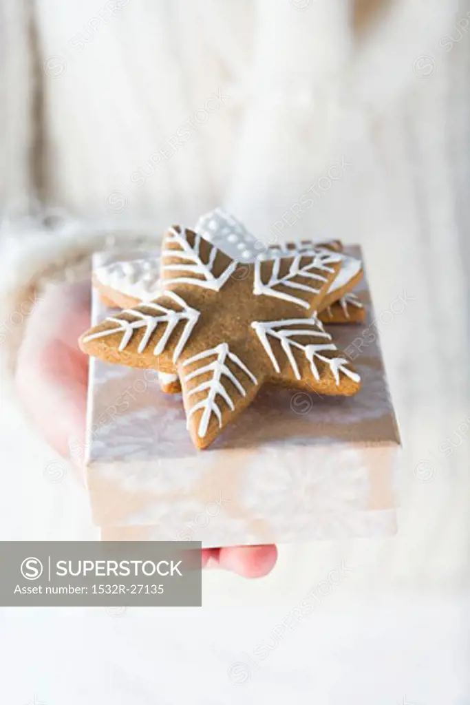 Hands holding gingerbread stars on small box
