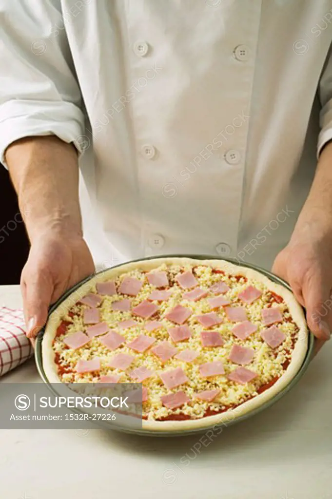 Topping a pizza with ham