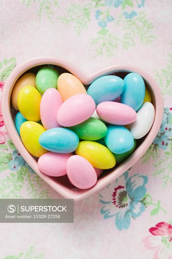 Coloured sugared almonds in pink heart-shaped dish