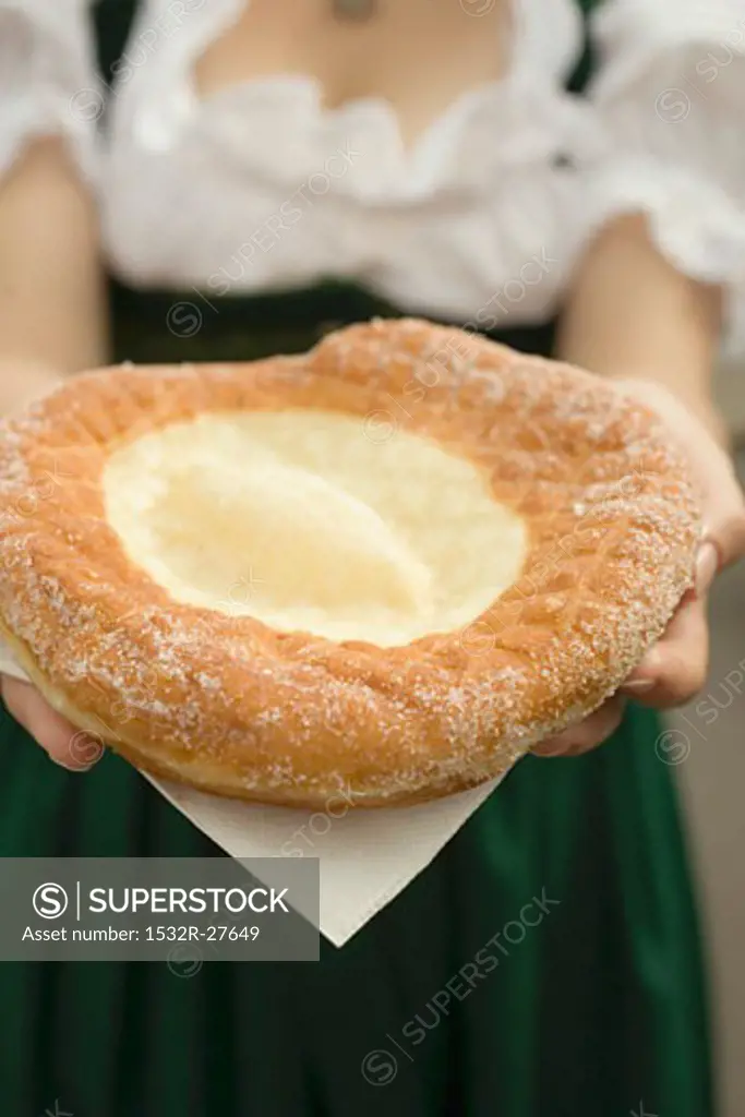 Woman holding Auszogene (Bavarian fried pastry) on napkin