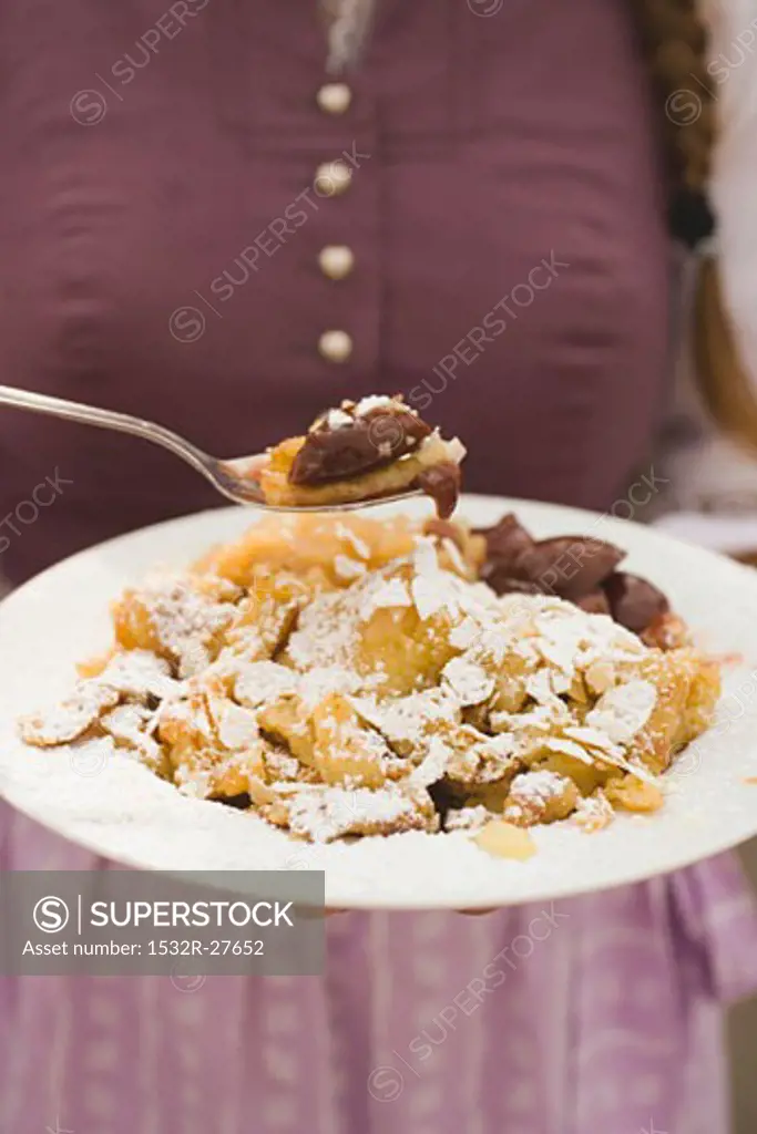 Woman holding plate of Emperor's pancake & stewed damsons