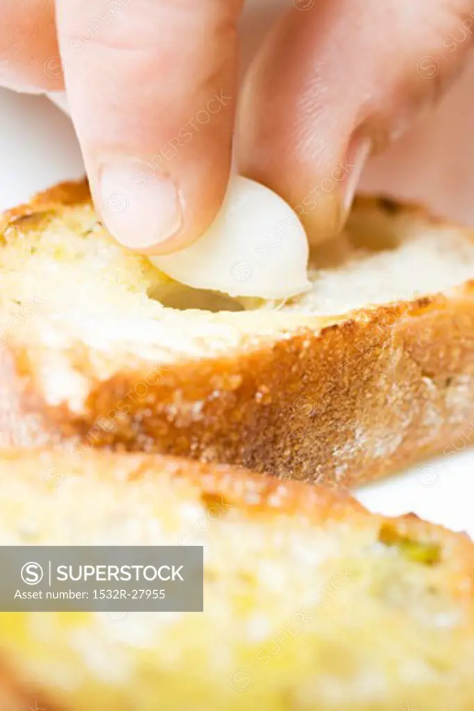 Filling baguette slice with clove of garlic