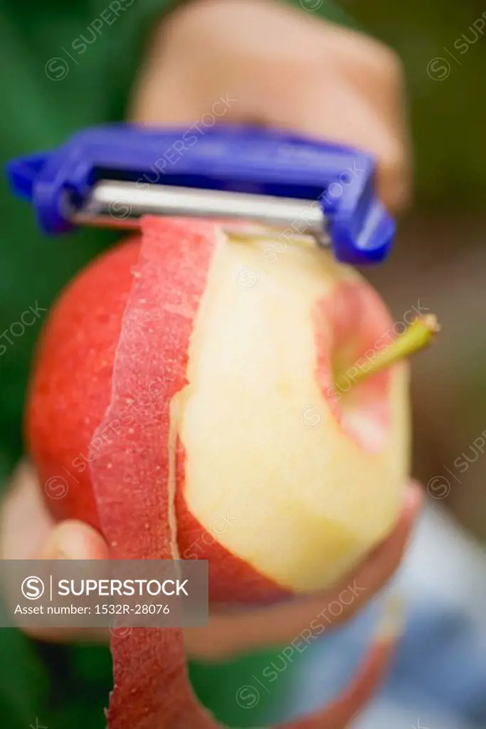Child's hands peeling a red apple