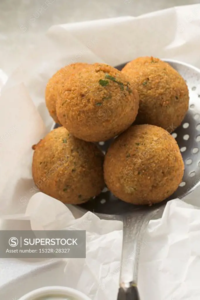 Falafel (chick-pea balls) on slotted spoon