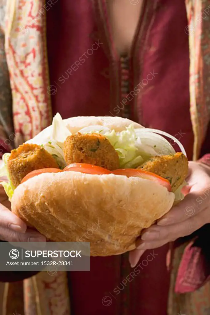 Woman holding flatbread filled with falafel (chick-pea balls)