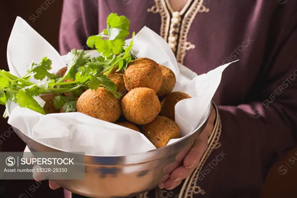 Woman serving falafel (chick-pea balls) in bowl
