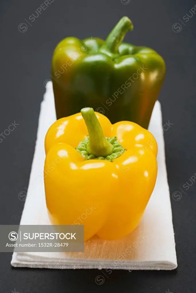 Two peppers (yellow, green) on white linen cloth
