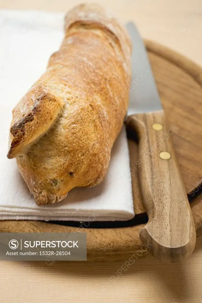 Baguette on breadboard with knife