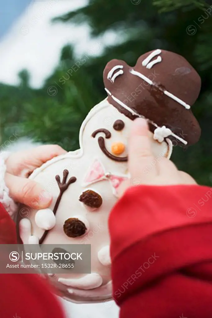 Child holding snowman biscuit