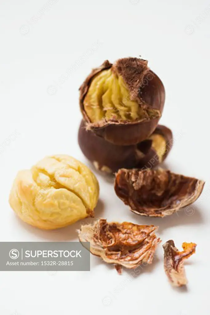 Several roasted chestnuts, one peeled