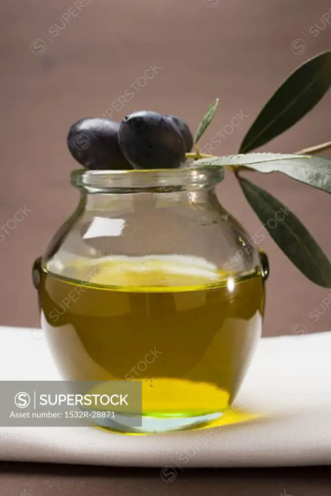 Olive sprig with black olives on jar of olive oil