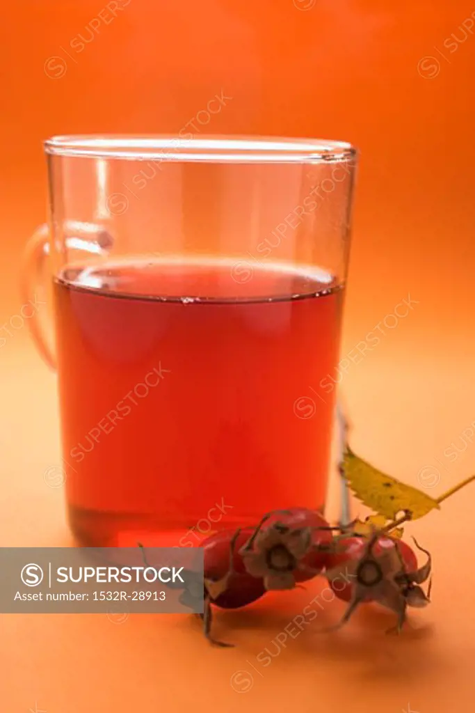 Rose hip tea in glass cup, sprig of fresh rose hips