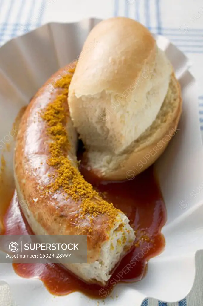Sausage with curry powder, ketchup & bread roll (partly eaten)