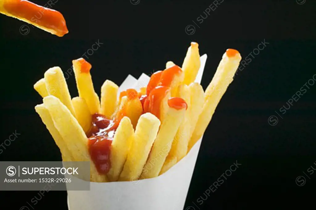 Chips with ketchup in paper cone, one above it